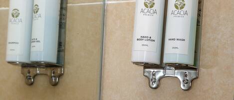 A bathroom with a mirror, two hand and body wash bottles, and a stack of white towels.