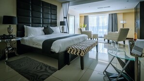 Una habitación de hotel moderna con una cama grande, una mesa de centro de vidrio, un sofá y una silla.