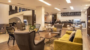 Un moderno vestíbulo de hotel con una zona de estar, una escalera y una cocina al fondo.