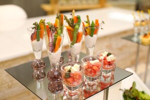 A table with various food items, including fruit and vegetable garnishes in clear glasses. - The Grand Mountain Hotel (Matale)