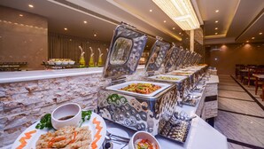 A buffet setup with various food items and a marble wall.
