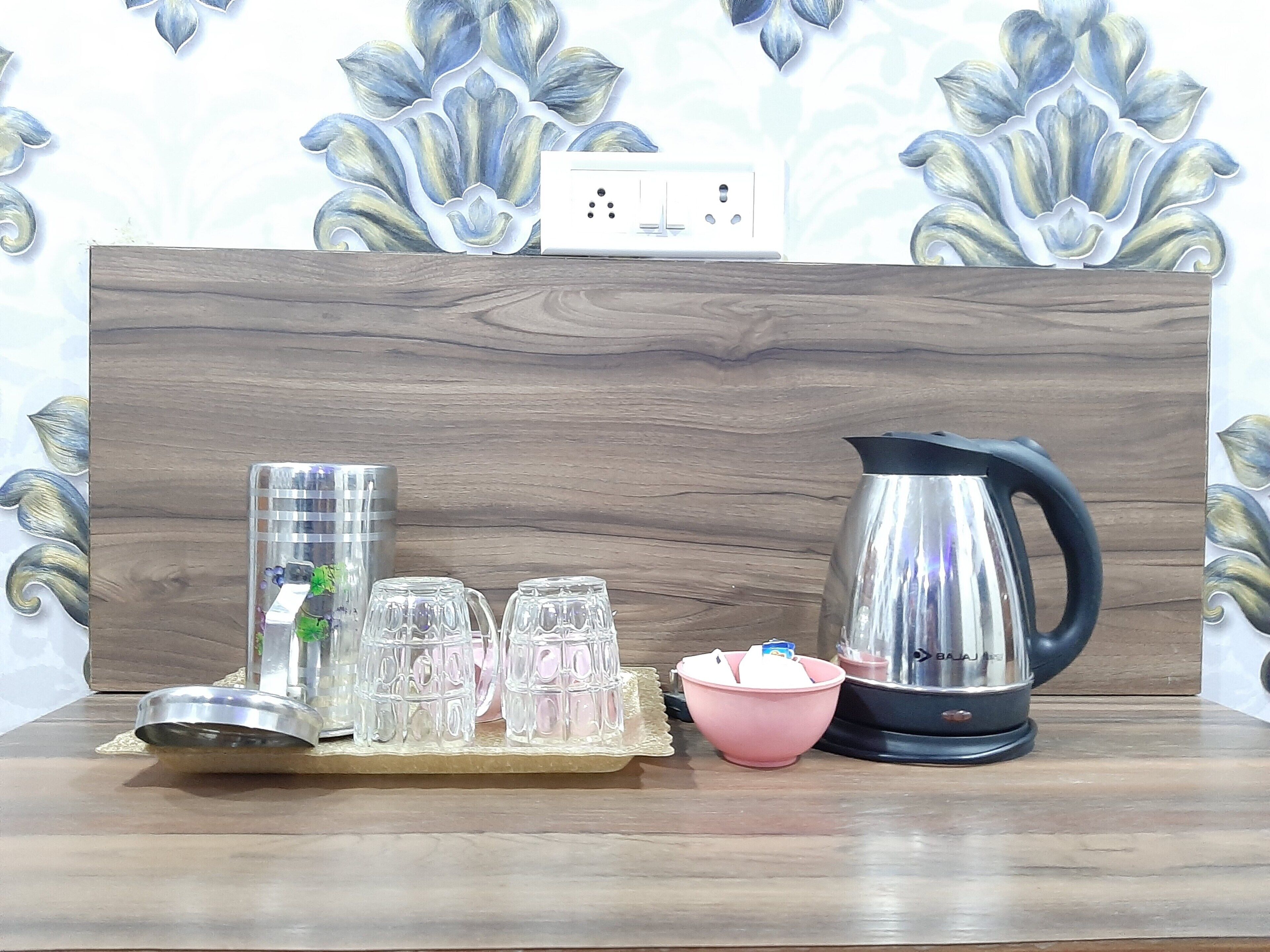 Una mesa de madera con un hervidor, un cuenco rosa y varios vasos de vidrio.