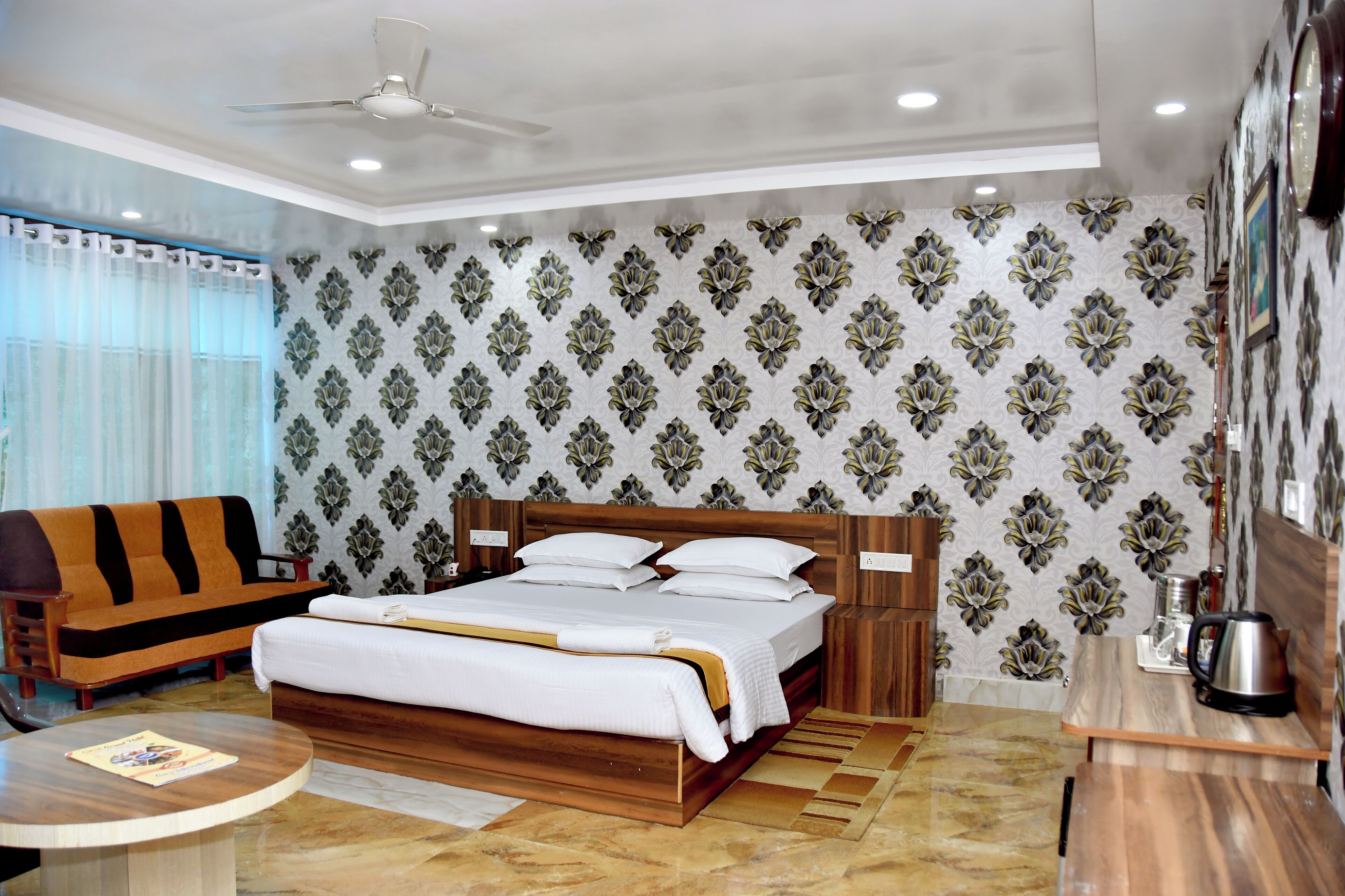 Ein Hotelzimmer mit Bett, einer Couch, einem Couchtisch und einer Wand mit dekorativem Muster.