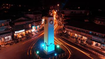 A clock tower in the center of a city square surrounded by shops and buildings.