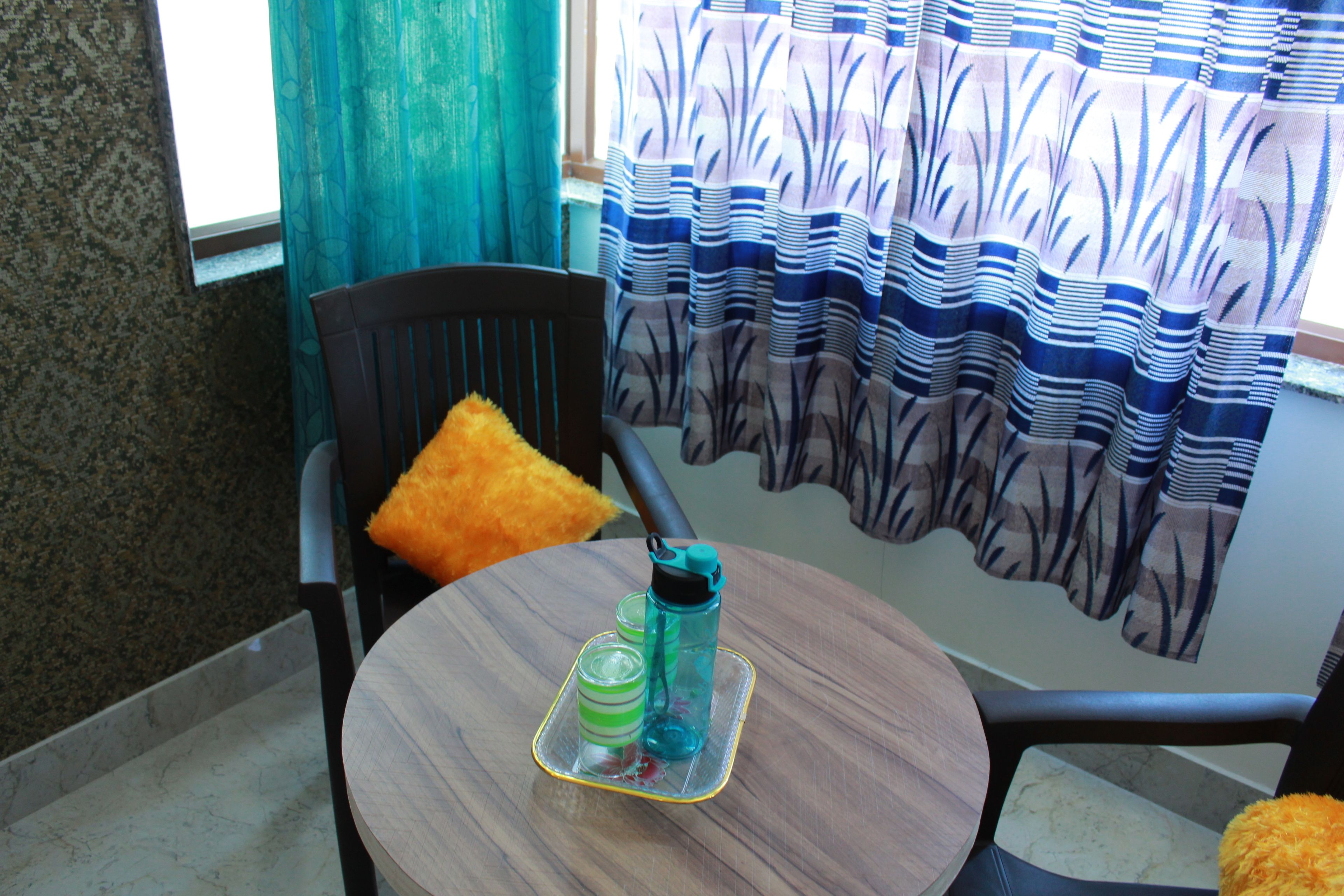 Un comedor con una mesa redonda, sillas y un ventanal con cortinas.