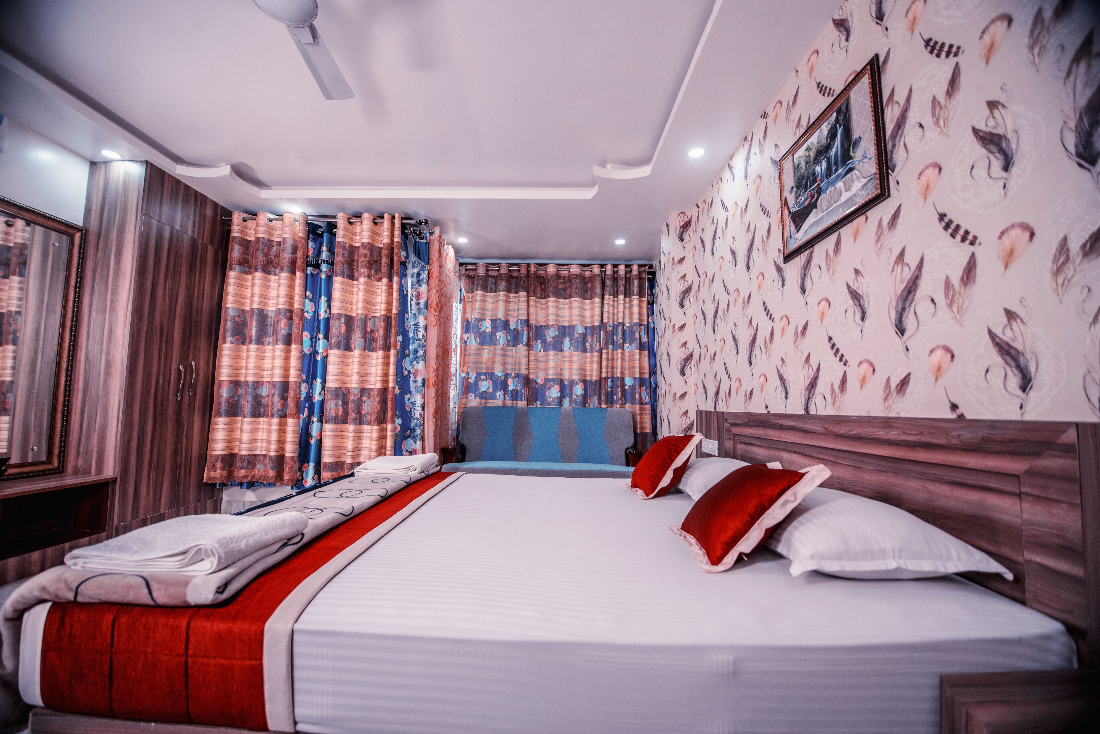 A hotel room with a large bed, wooden headboard, and curtains with a floral pattern.