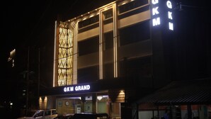 A building with a prominent 'GK Grand' sign, featuring a modern facade with vertical lighting accents and a patterned design on the left side. - GKM Grand Hotel (Port Blair)