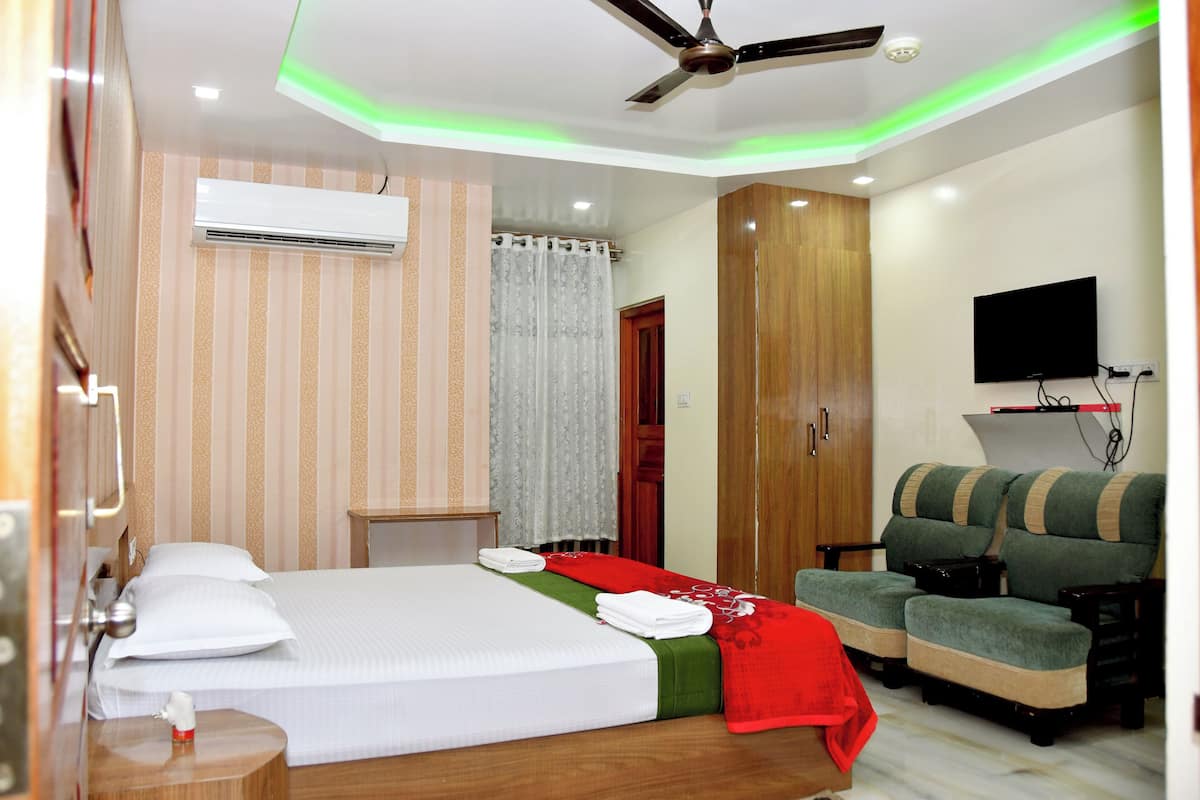 A hotel room with a bed, a desk, a television, and a seating area.