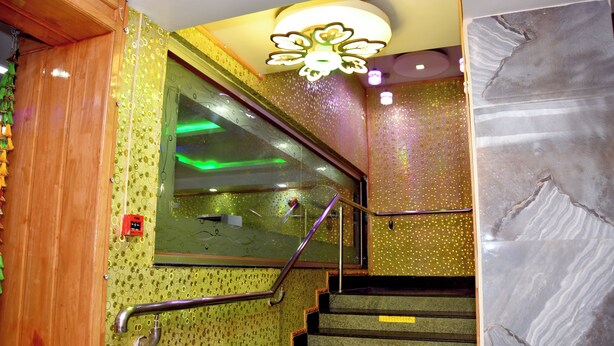 A staircase with a handrail, a green patterned wall, and a mirror. - GKM Grand Hotel (Port Blair)