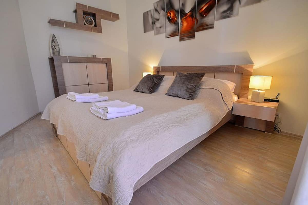 Uma cama bem arrumada com cabeceira, mesa de cabeceira com abajur e obras de arte na parede.