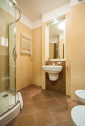 A bathroom with a glass shower enclosure, a white sink, and a mirror above the sink.