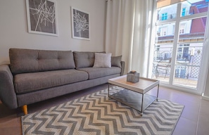 Uma sala de estar moderna com um sofá cinzento, uma mesinha de centro e um tapete estampado.