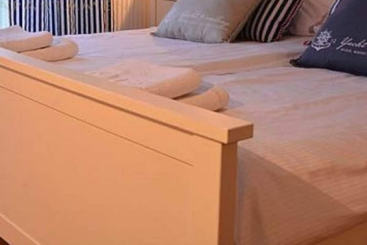 Quarto com uma cama, mesa de cabeceira e janela com cortinas.