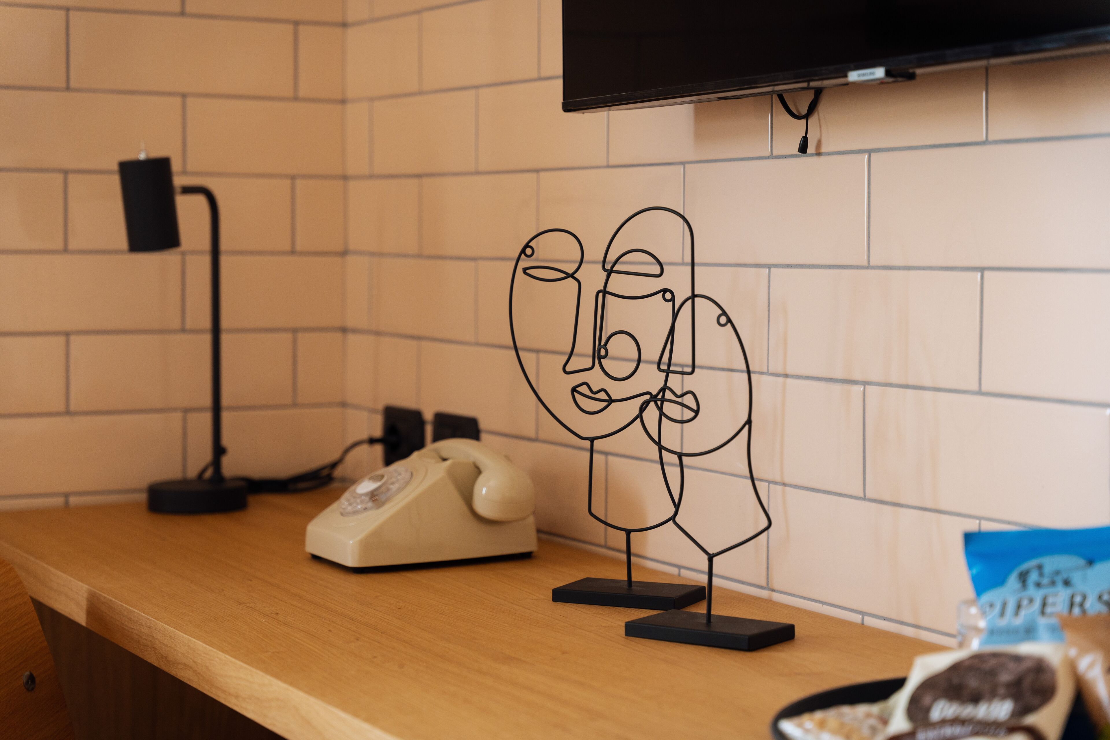 A kitchen counter with a vintage telephone, a wall-mounted television, and a bag of chips.