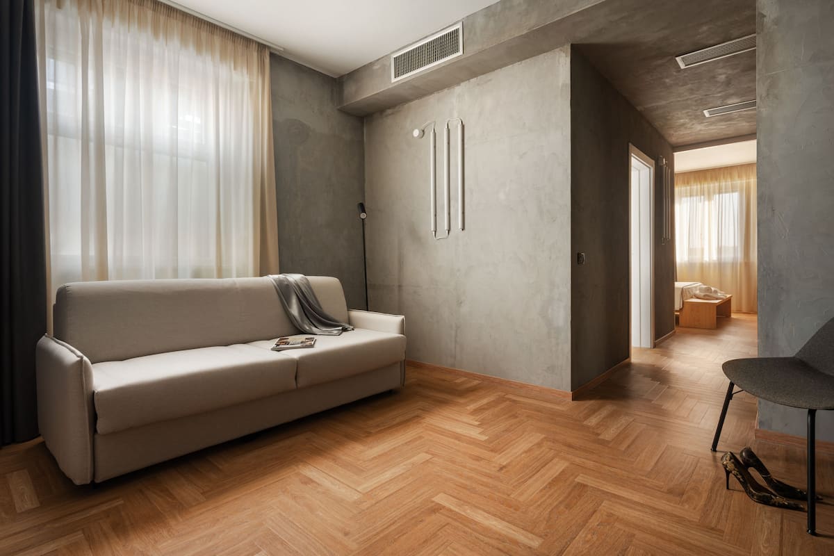 Un salon moderne avec un canapé, un plancher en bois et un fauteuil.