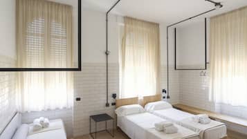 Una camera d'albergo con due letti, un tavolino, uno specchio e una finestra con tende.