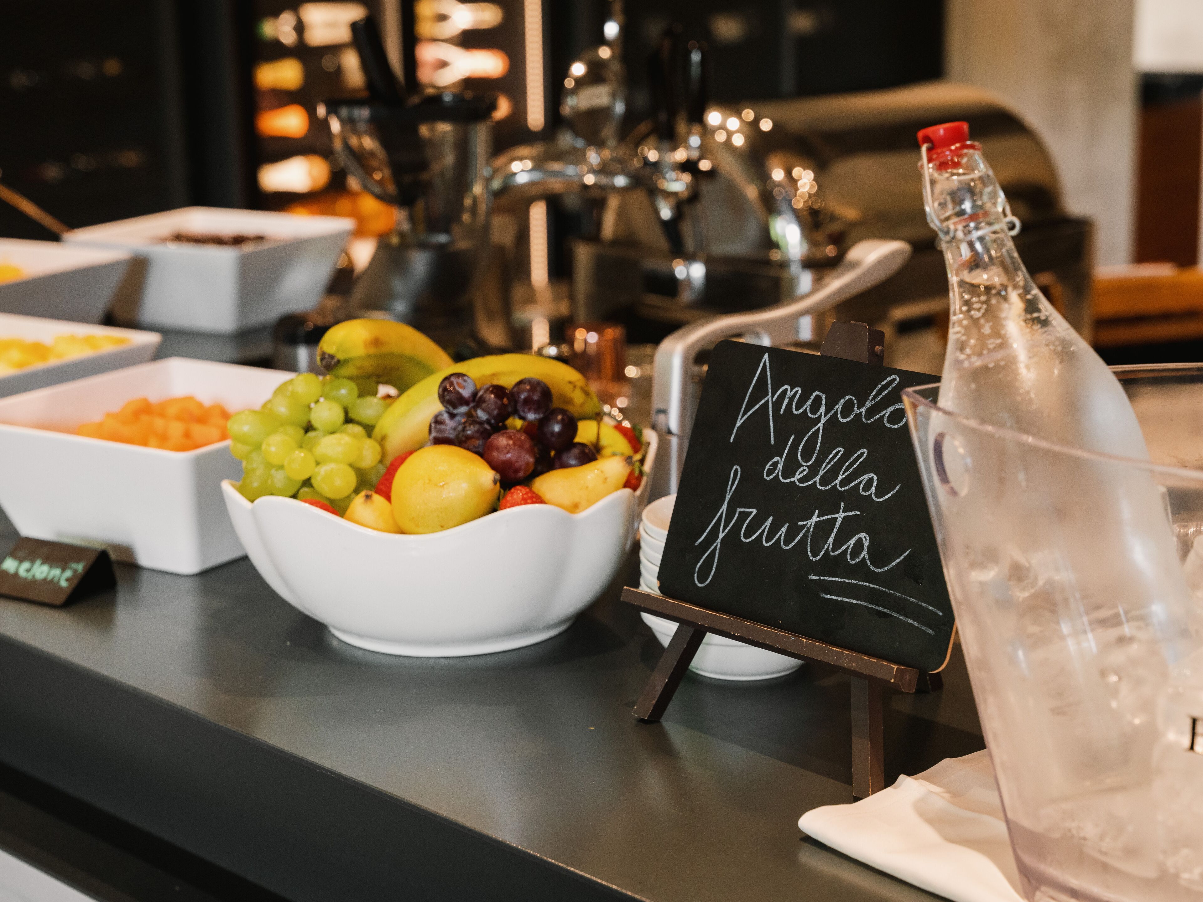 Een ontbijtbuffet met diverse soorten fruit en een bordje met de tekst 'Angolo della frutta'.