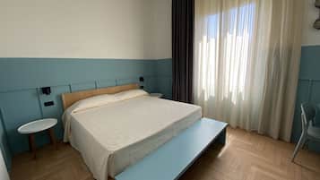 Een keurig opgemaakt slaapkamer met een bed, nachtkastjes, een bankje en een raam met gordijnen.
