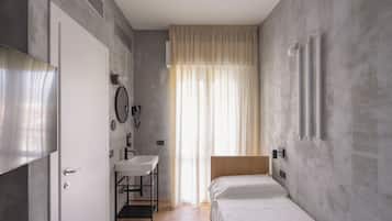 Une chambre à coucher avec un lit, une table de chevet, un miroir et une fenêtre avec des rideaux.