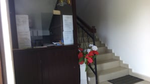 A staircase with a wooden handrail and a white wall. - Hôtel Lobé (Kribi)