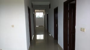 A narrow, well-lit hallway with a door at the end leading to a bright room. - Hôtel Lobé (Kribi)
