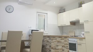 Una cocina moderna con armarios blancos, una pared de acento de piedra y luces empotradas en el techo.