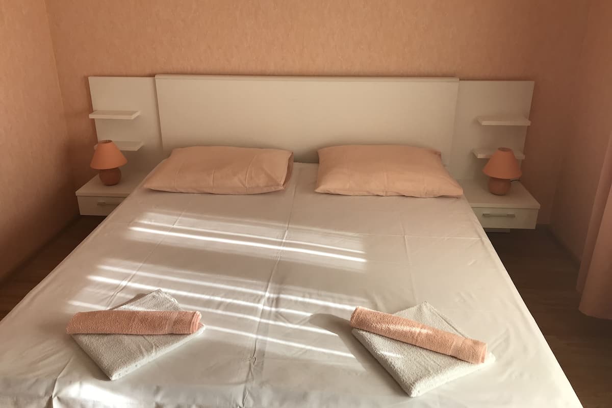 A neatly made bed with two pillows and two folded towels.