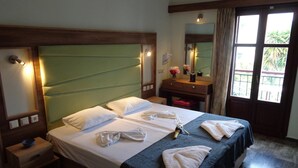 Une chambre d’hôtel avec un grand lit, une table de chevet, une commode, un miroir et une fenêtre avec des rideaux.