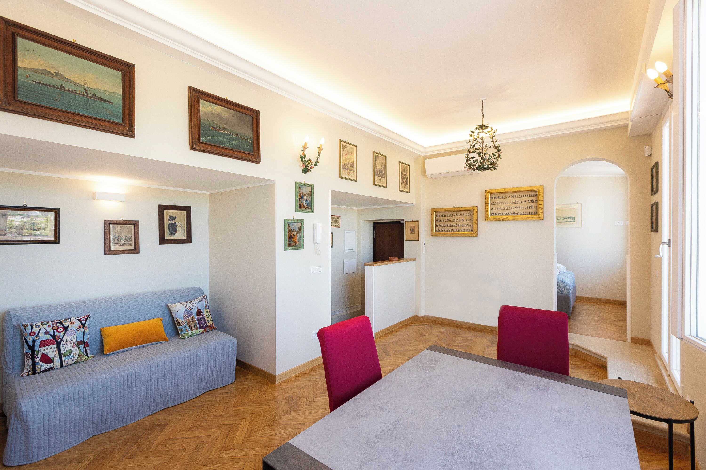 A dining area with a table, chairs, a sofa, and a staircase leading to another room.