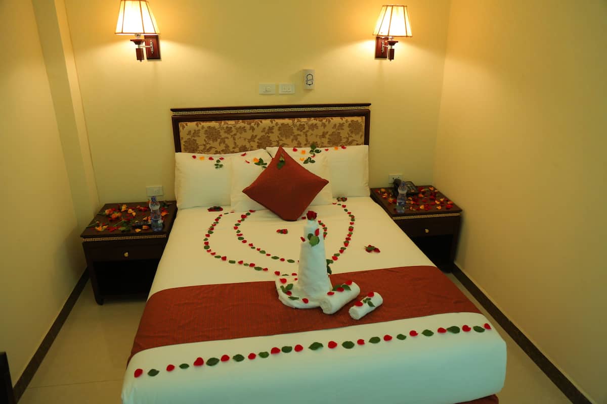 A hotel room with a bed, two nightstands, and a wall-mounted lamp.