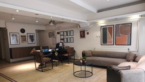 Een moderne woonkamer met een bank, stoelen, een salontafel en een bureau met een computer.