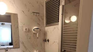 Een badkamer met toilet, wastafel, spiegel en douche.