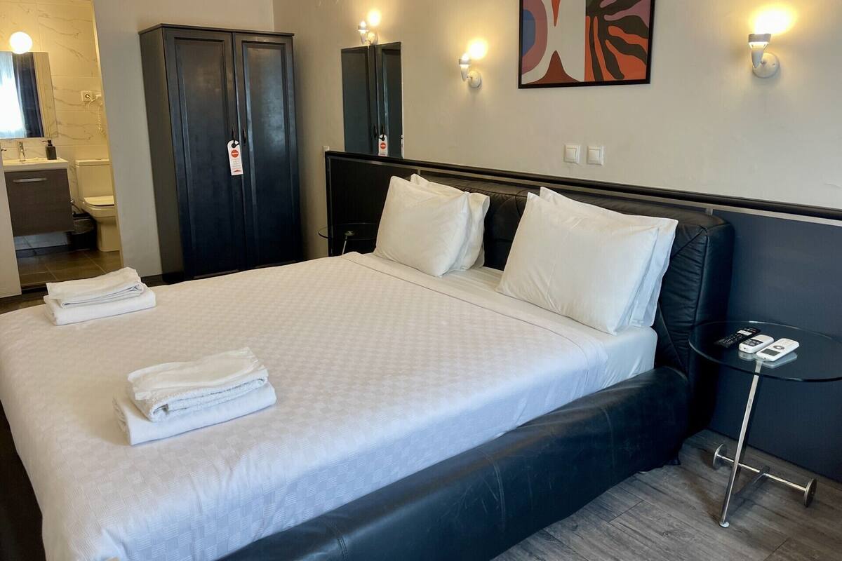 A hotel room with a bed, a desk, a chair, a wardrobe, and a bathroom.