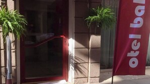 Een rode luifel boven een deuropening, een bloempot aan de linkerkant en een vlag met de tekst 'otel balca'.