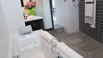 Un baño moderno con una bañera grande, un espejo y un perchero para toallas.