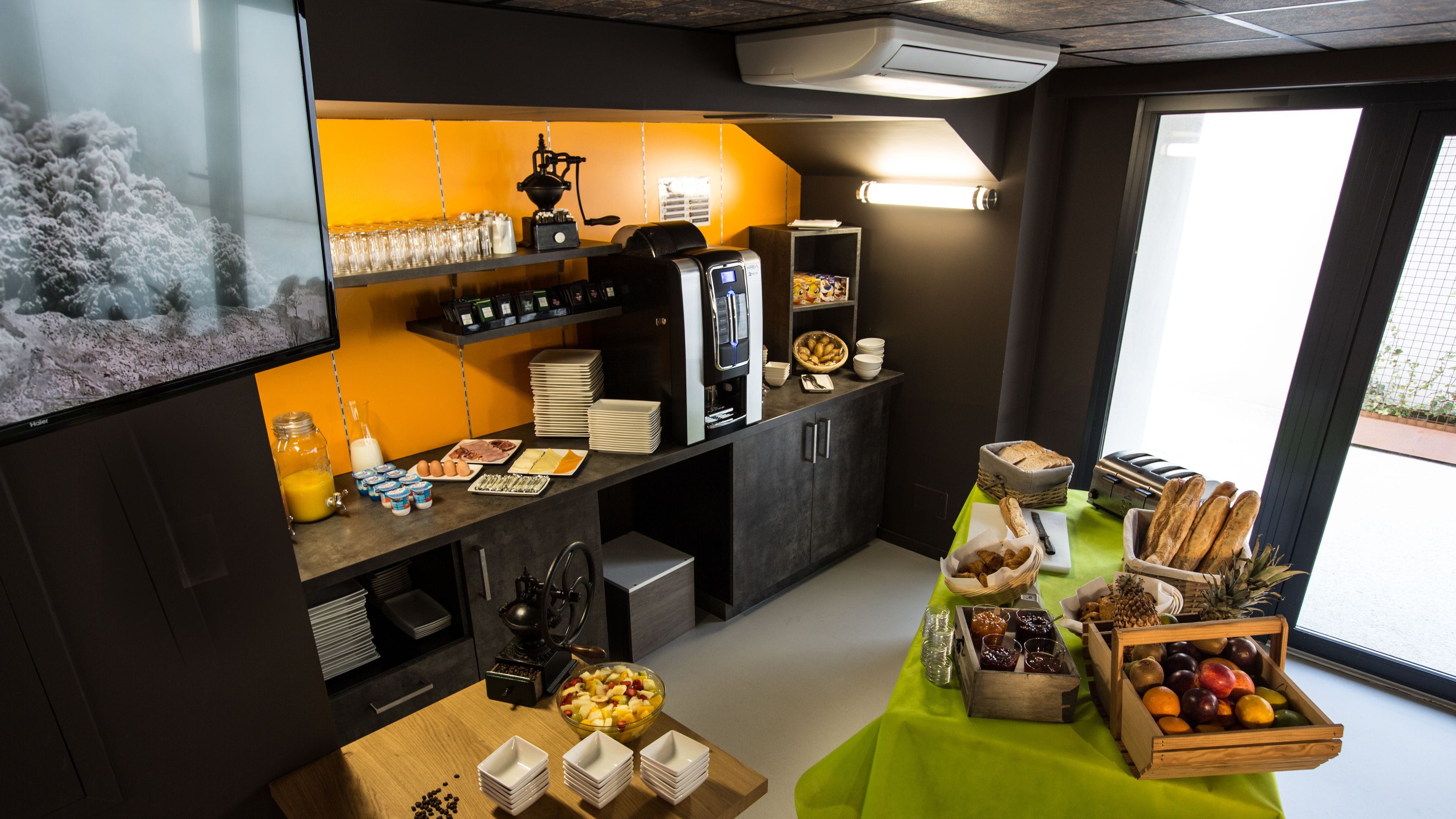 Een moderne keuken met een koffieapparaat, ontbijtartikelen en een presentatie van fruit.