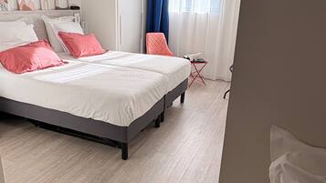 Un dormitorio moderno con una cama grande, una mesita pequeña y una silla.