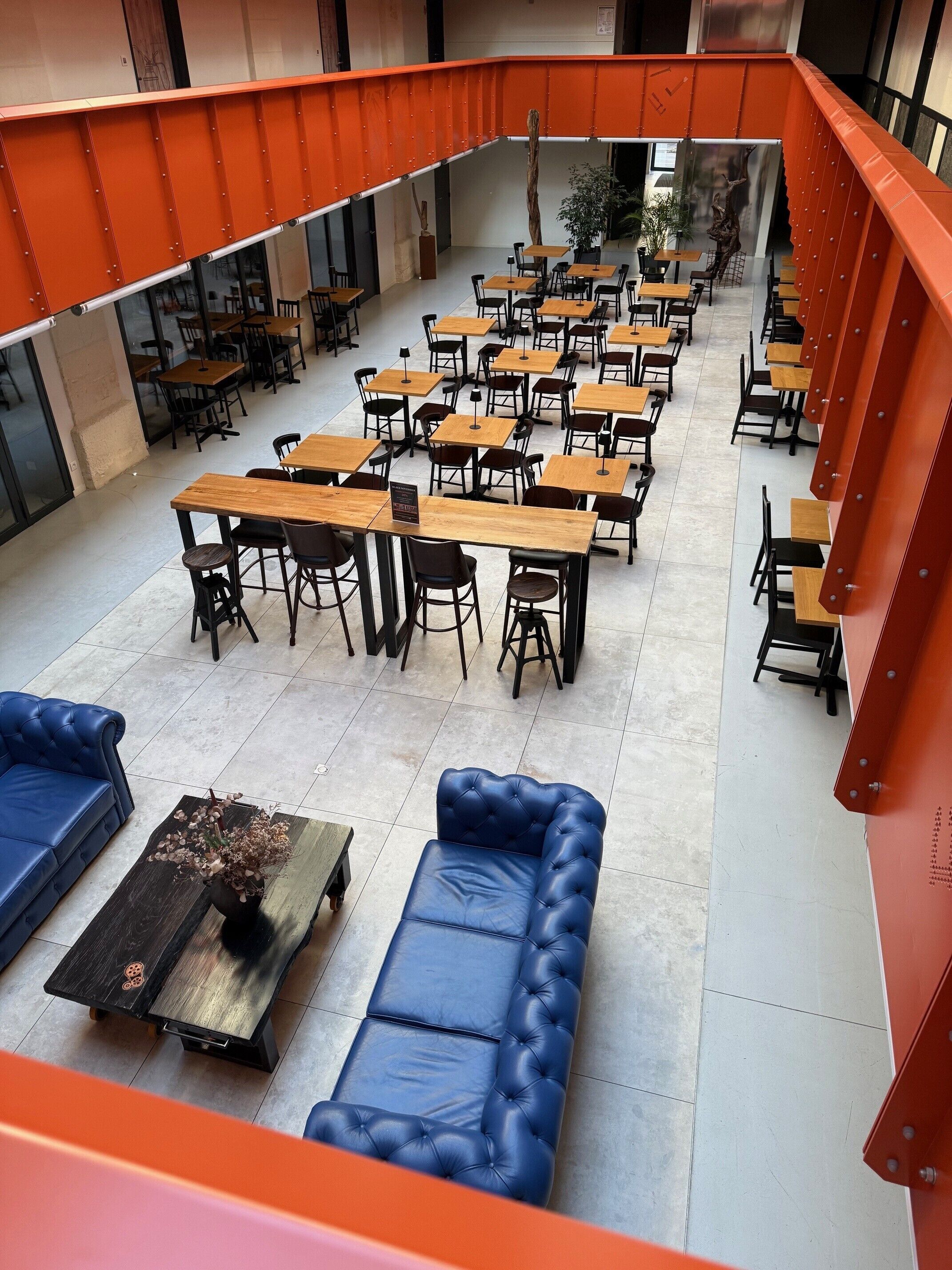 A spacious indoor seating area with multiple tables and chairs, a blue sofa, and a decorative table with flowers.