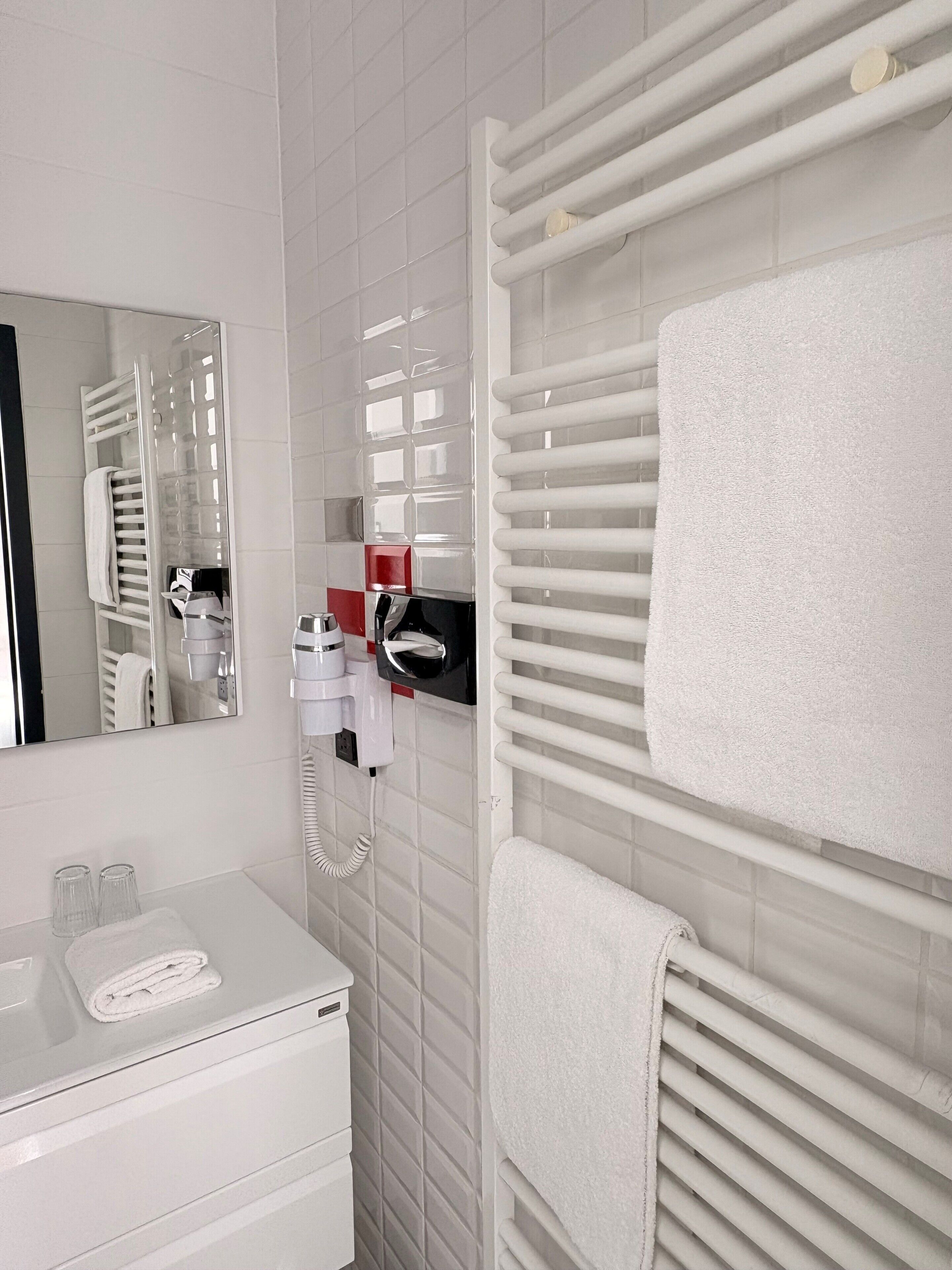 A bathroom with a white sink, a mirror, a towel rack, and a hairdryer.