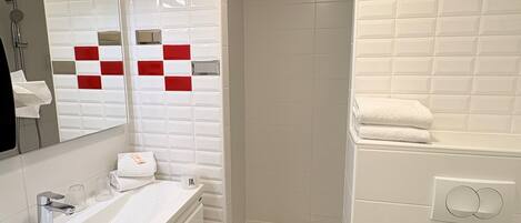 A modern bathroom with a white vanity, a shower, and a toilet.