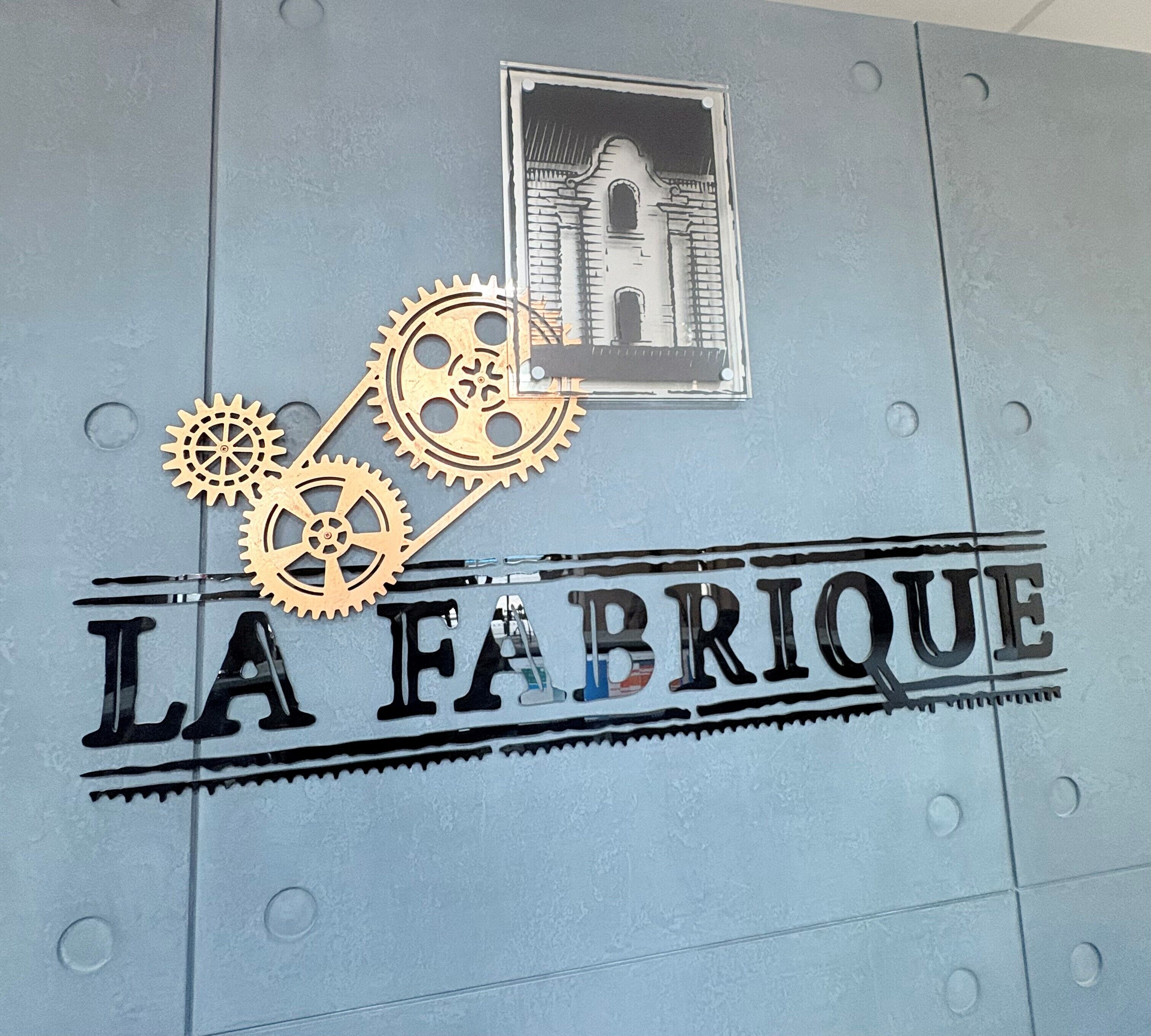 A wall with the text "LA FABRIQUE" and a small picture of a building.