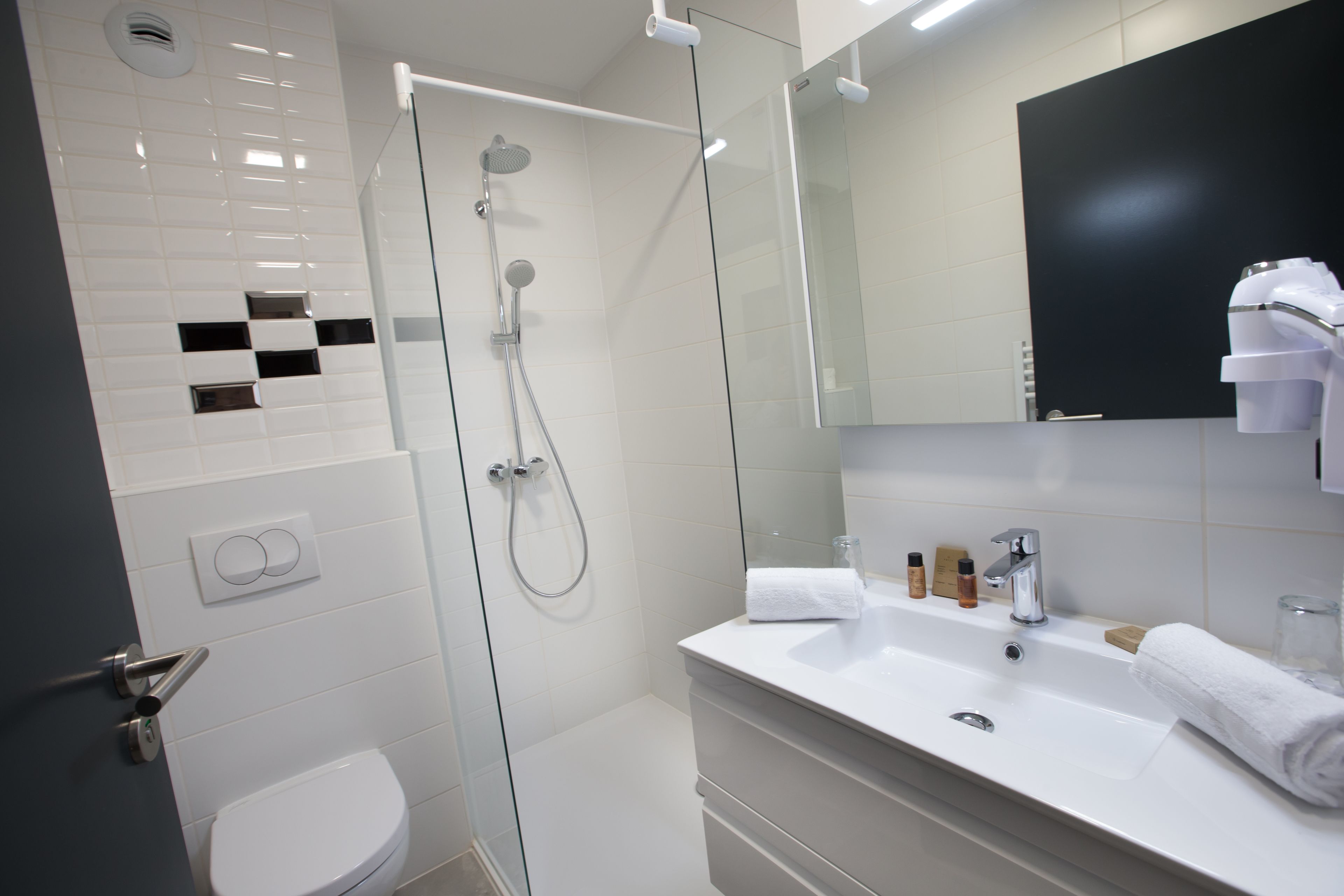 Un bagno moderno con doccia vetrata, lavandino bianco e uno specchio grande.