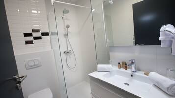 Un bagno moderno con doccia vetrata, lavandino bianco e uno specchio grande.