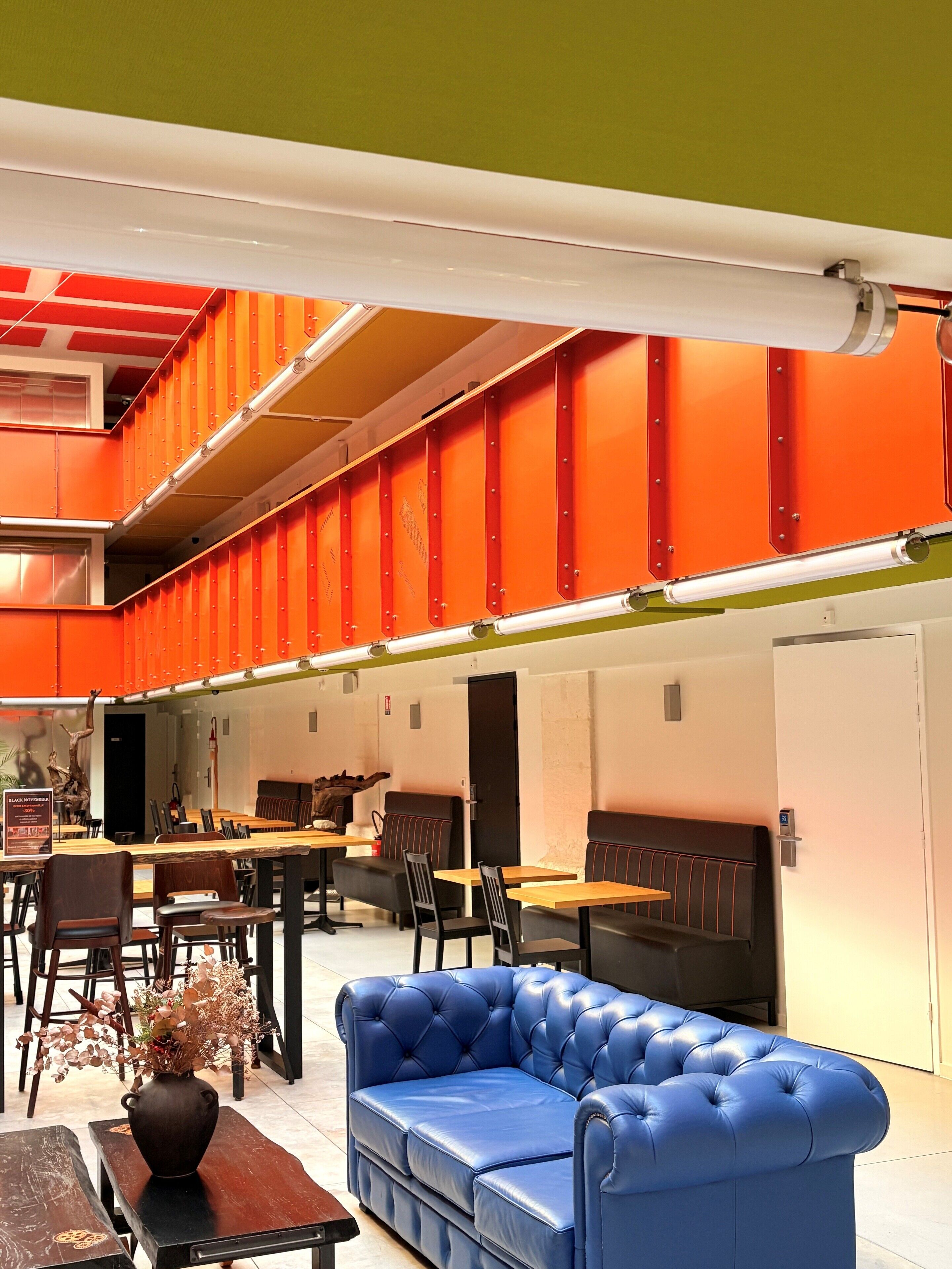 A modern interior with a blue sofa, wooden tables, and orange accents.