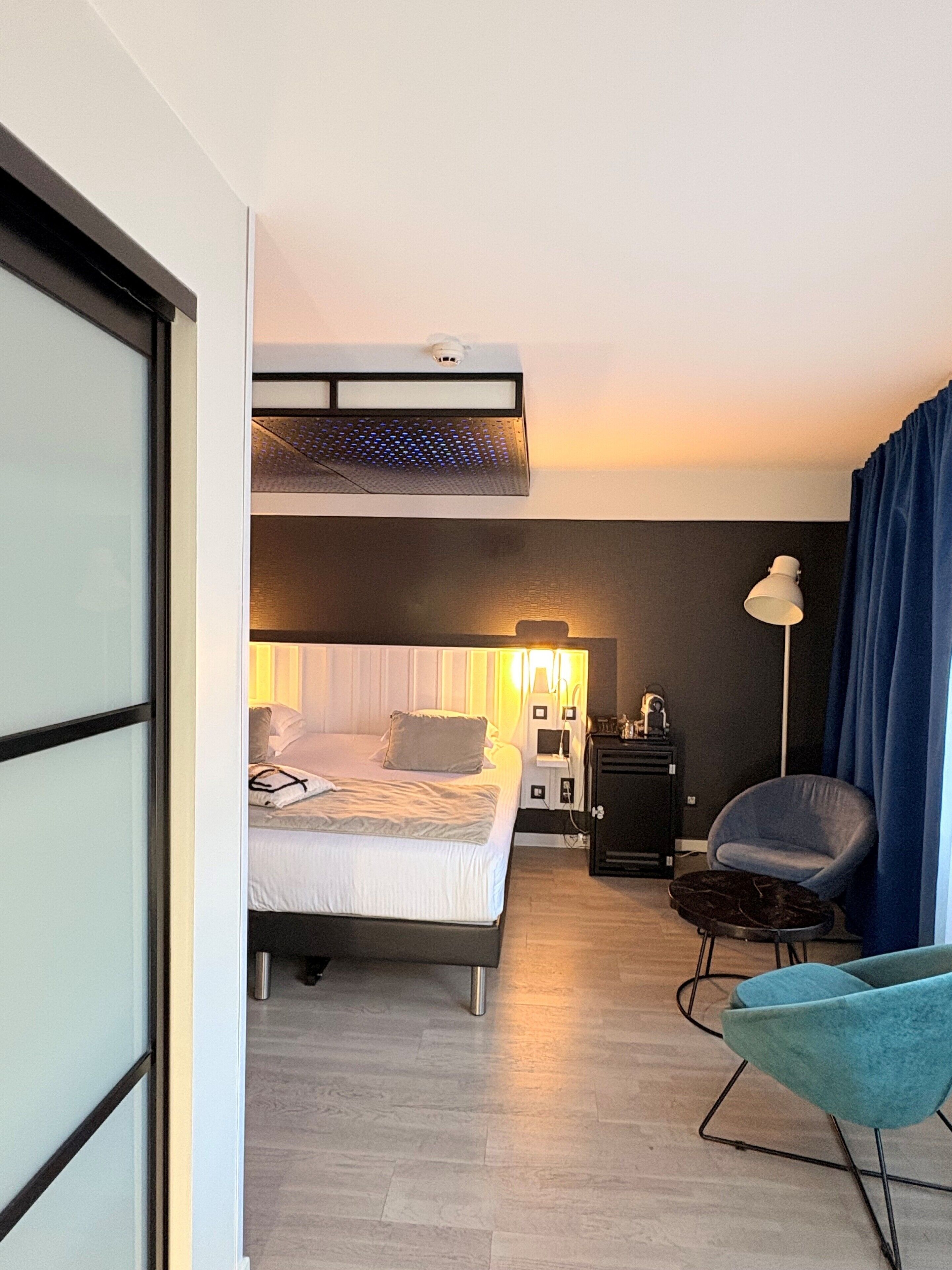 A hotel room with a bunk bed, a desk, a chair, and a lamp.