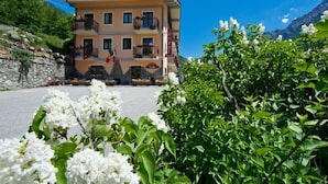 A two-story hotel with balconies, a stone wall, and a mountain backdrop. - Hotel Valentino (Bionaz)