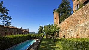 Un edificio histórico con piscina, muros de piedra y una torre.