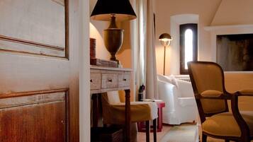 A cozy room with a wooden door, a lamp, a chair, and a white sofa.