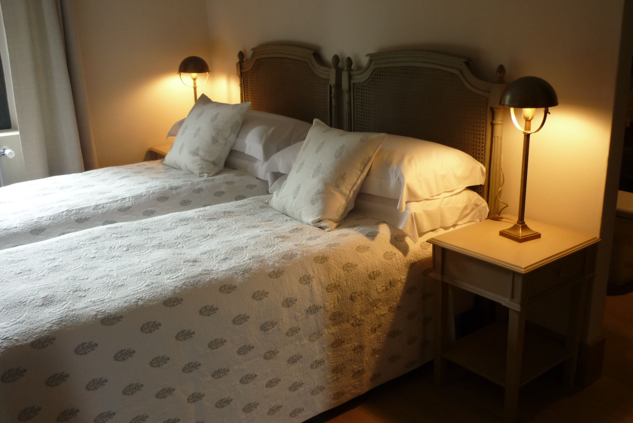 Ein Doppelbett mit einem floralen Bettbezug, zwei Nachttischlampen und ein Nachttisch.