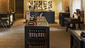 Zona de bar con paredes de ladrillo, una barra central y estantes llenos de botellas.